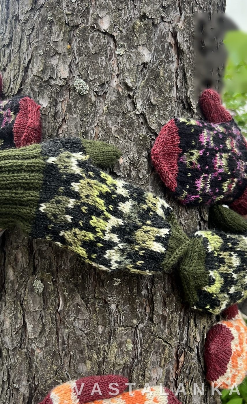 Three pairs of Kettu fox-motif mittens hugging a pine tree
